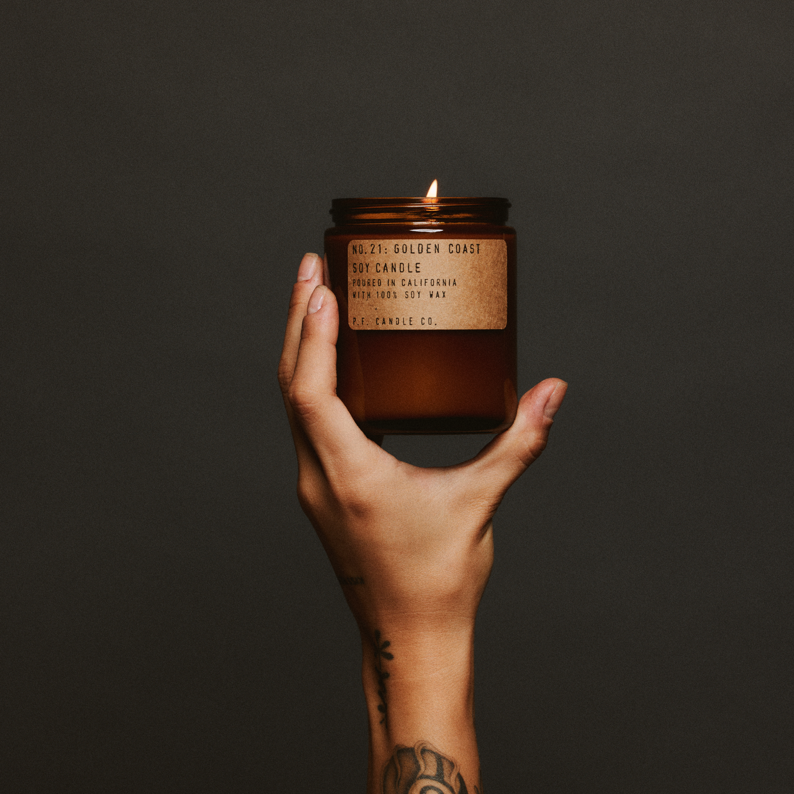 Golden Coast home fragrance held in a hand against a softly lit background
